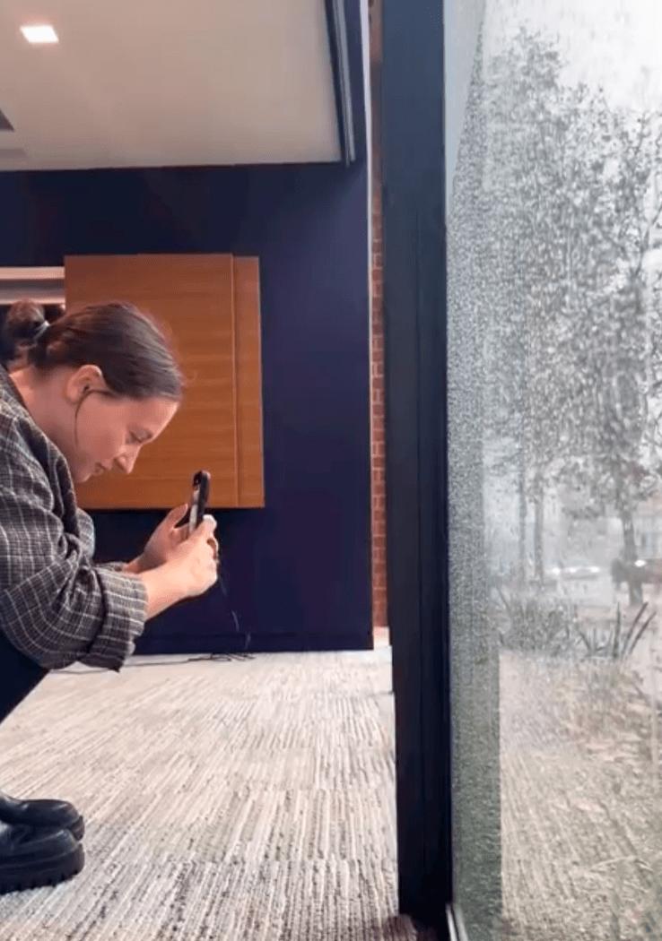 Employee Capturing Rainy Day Through Glass Window at Kovac Design